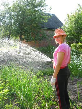 The girl watering a kitchen garden in the country