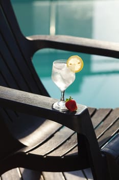 Swimming pool, lounge, a wine glass with ice, lemon and strawberry