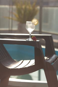 Swimming pool, lounge, a wine glass with ice, lemon and strawberry