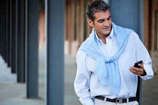 Smart casual man using cell phone with hand in pocket