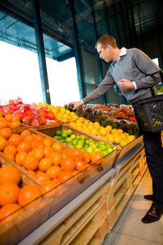 A man in a grocery store buying fruits and vegetables