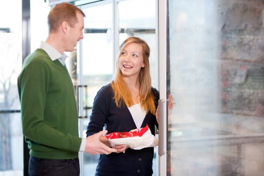 A happy couple choosing groceries from the frozen food section in a supermarket