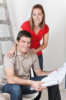 Portrait of young happy couple together with blueprints