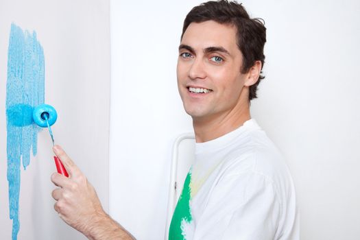 Close-up portrait of happy man painting wall with roller