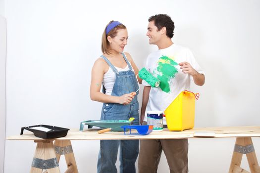 Smiling woman painting husband's t-shirt with roller