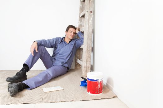 Tired young man leaning on ladder and sleeping