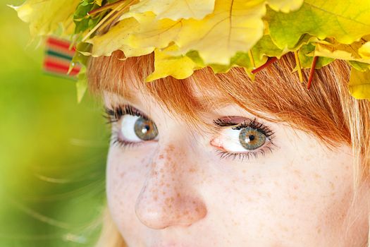 portrait of a beautiful young redhead teenager woman in a wreath of maple leaves