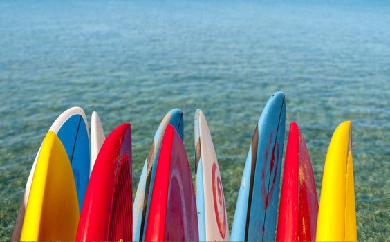 TIps of surf board or surfboards by side of calm blue transparent clear sea