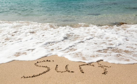 Sand drawing on warm beach by ocean surf in Caribbean spelling Surf