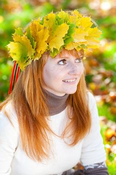 portrait of a beautiful young redhead teenager woman in a wreath of maple leaves