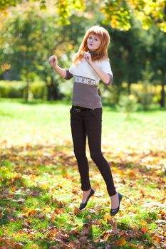 jumping young redhead teenager woman in the forest