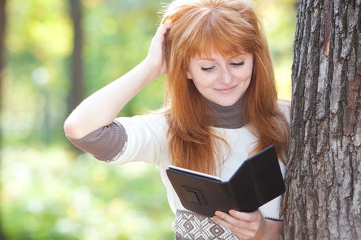 portrait of a beautiful young redhead teenager woman reading a book