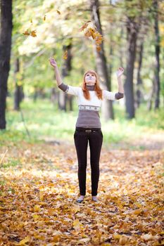 young redhead teenager throwing leaves woman in the forest  