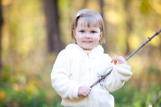 beautiful little girl with a stick on the autumn forest