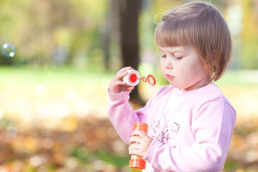 beautiful little girl making  bubble blower on the autumn forest