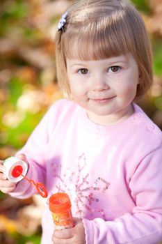 beautiful little girl making  bubble blower on the autumn forest