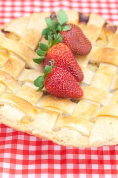 apple pie and a strawberry on plaid fabric