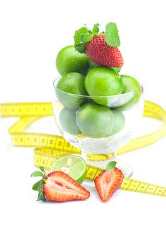 lime in a glass cup, measuring tape, strawberry and mint isolated on white