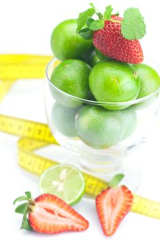lime in a glass cup, measuring tape, strawberry and mint isolated on white