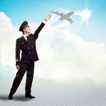 pilot in the form of extending a hand to a flying airplane on the background of clouds and sun