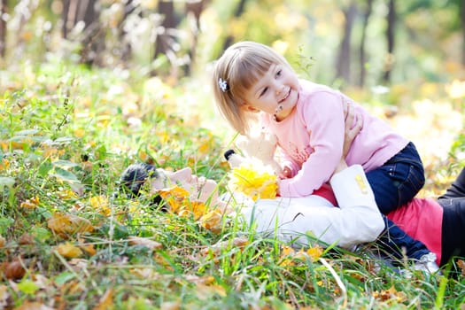 beautiful young mother and her daughter lying on the autumn leaves