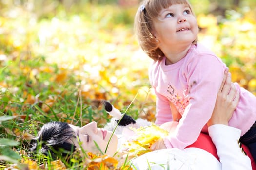 beautiful young mother and her daughter lying on the autumn leaves