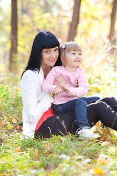 beautiful young mother and her daughter on the autumv forest