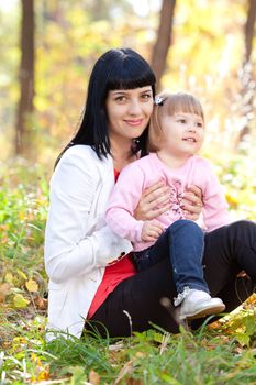 beautiful young mother and her daughter on the autumv forest