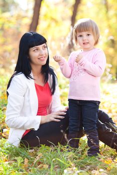 beautiful young mother and her daughter on the autumv forest