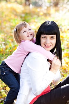 beautiful young mother and her daughter on the autumv forest