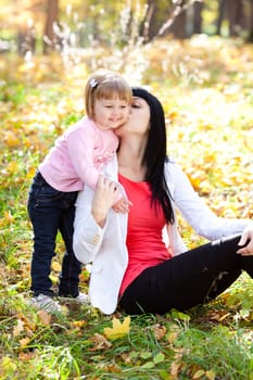 beautiful young mother and her daughter on the autumv forest