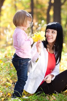 beautiful young mother and her daughter on the autumv forest