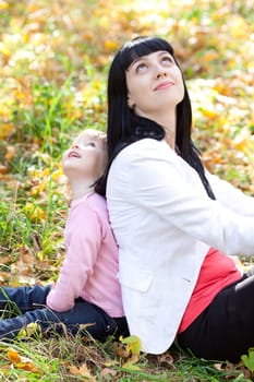 beautiful young mother and her daughter looking up in the autumn forest