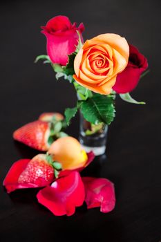 bouquet of colorful roses in a vase and strawberry on a wooden table