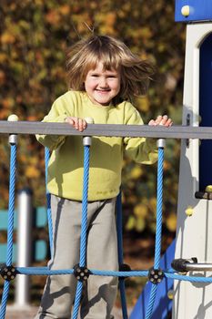 young child playing on colorful playground in autumn