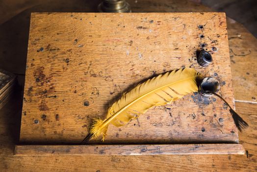 High angle shot of old quill and ink well on wooden writing desk