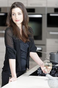 Beautiful young woman enjoying a glass of wine in her kitchen.