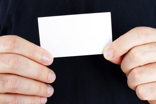 Man hands holding a blank business card ready for your text over black shirt.