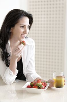 Attractive young woman enjoying a fresh fruit breakfast at home.