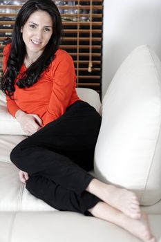 Beautiful woman relaxing on a white sofa in an elegant living room.