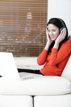 Attractive woman sat on a white sofa listening to music