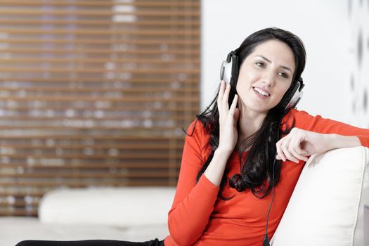 Attractive woman sat on a white sofa listening to music