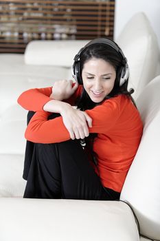 Attractive woman sat on a white sofa listening to music