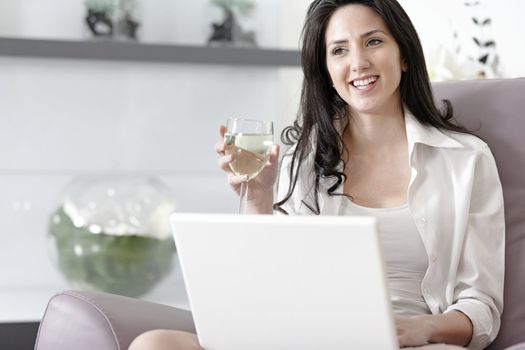 Beautiful young woman enjoying a glass of wine in her elegant living room.