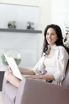 Attractive woman using her laptop in her living room.