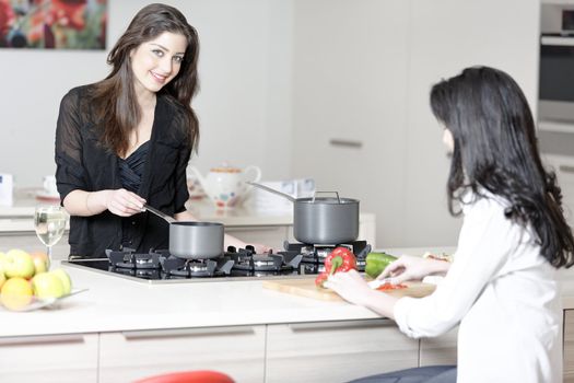 Two friends in a kitchen catching up preparing dinner.