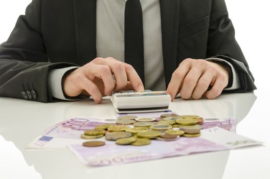 Detail of businessman working on calculator counting expenses. With Euro coins and banknotes on his white table.