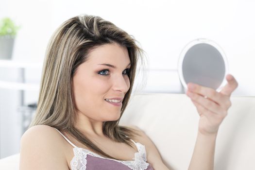 young blond woman looking in a  mirror