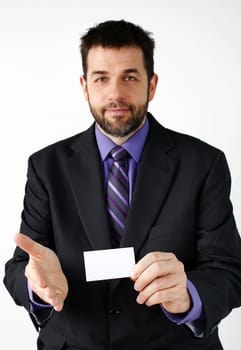 Middle aged man smiling while presenting his hand to meet a colleague while holding a blank business card, great business concept.