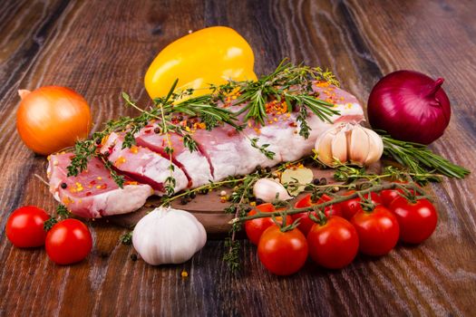 Raw fresh meat on cutting board with condiments and fresh vegetables